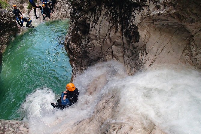 A canyoner abseiling into a turquoise pool in the Susec gorge above Bovec